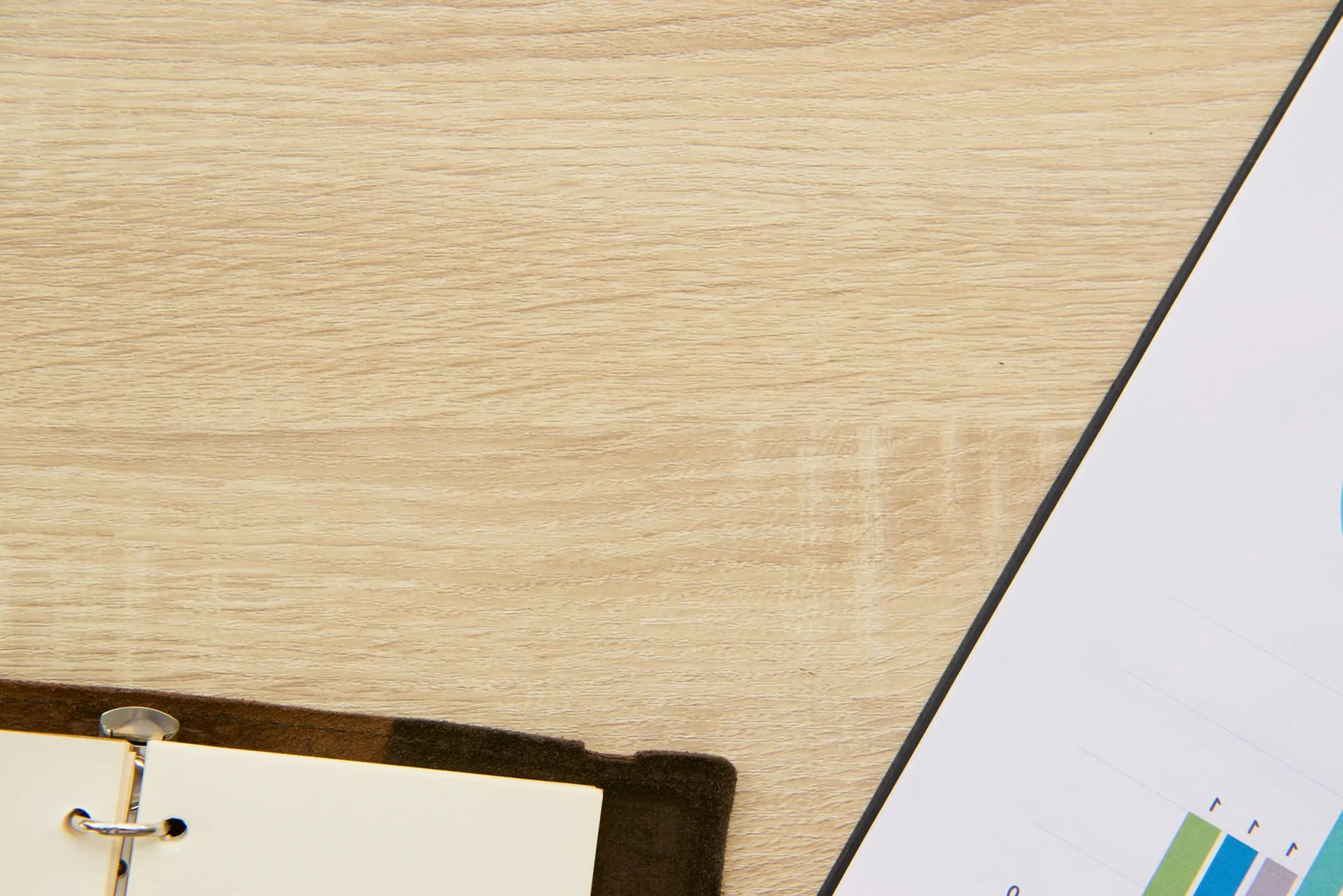 Cahier ouvert sur un bureau en bois avec un stylo, vue de dessus