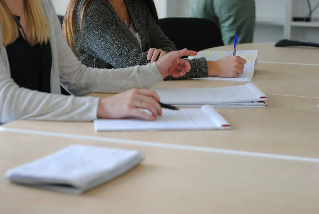 Deux personnes prenant des notes sur des documents posés sur une table de travail